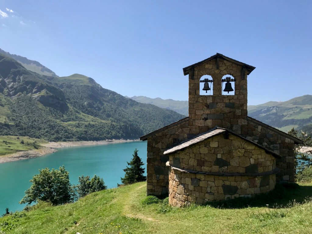 Stone chapel with bells above a turquoise lake